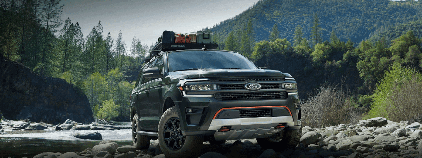 Ford Truck driving through rocky terrain with mountains in the background