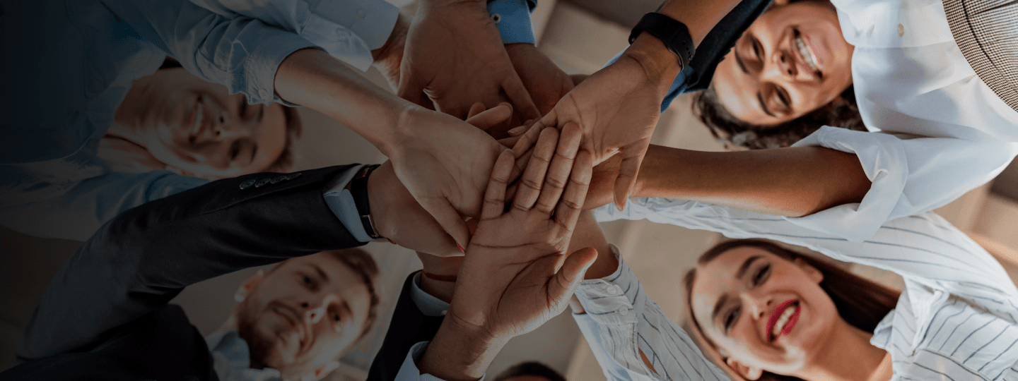 A group of team members putting all hands in a circle as a group
