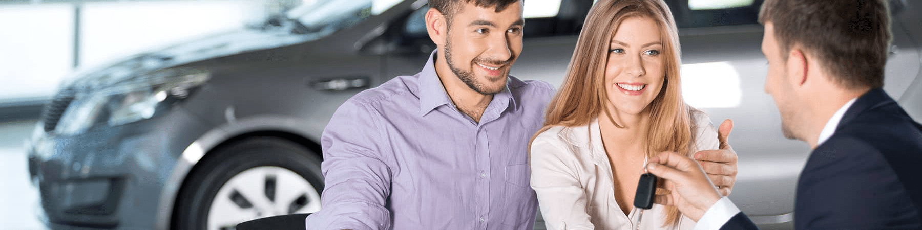 happy couple receives car keys from car dealer