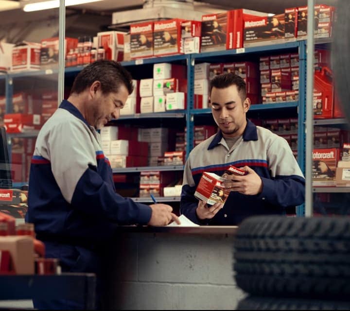 Two Parts Technicians are looking over parts in the Ford Parts Center. 