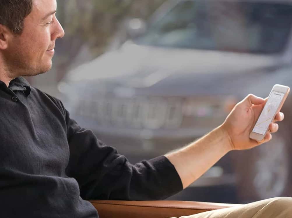 a-man-holding-mobile-sitting-in-front-of-window