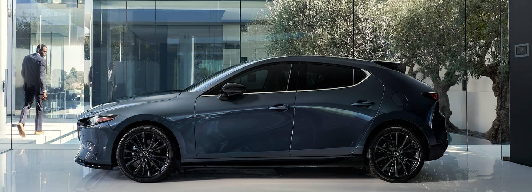 2022 Mazda 3 hatchback in front of tree and glass wall