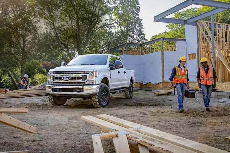 2021 Ford Super Duty Pickup parked by house construction site with two workers nearby