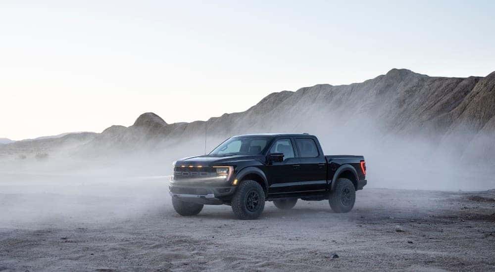 A black 2021 Ford F-150 Raptor is shown with dust settling after leaving a Ford dealer near you.