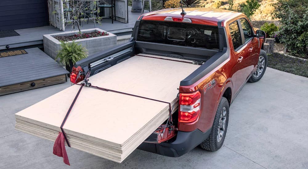 A red 2022 Ford Maverick is shown from a high angle with wood loaded in the bed.