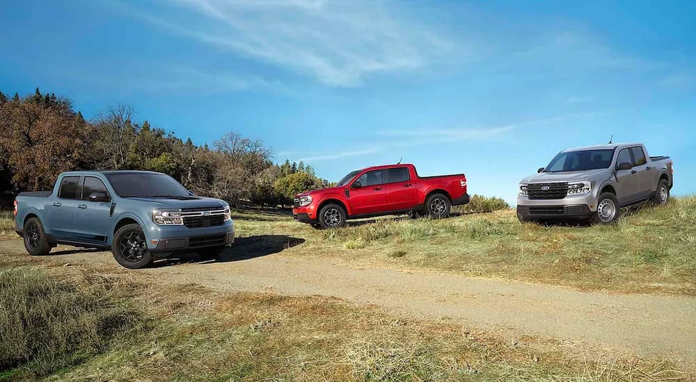 A blue, a red, and a silver 2022 Ford Maverick are shown in a field after visiting a Ford dealership.