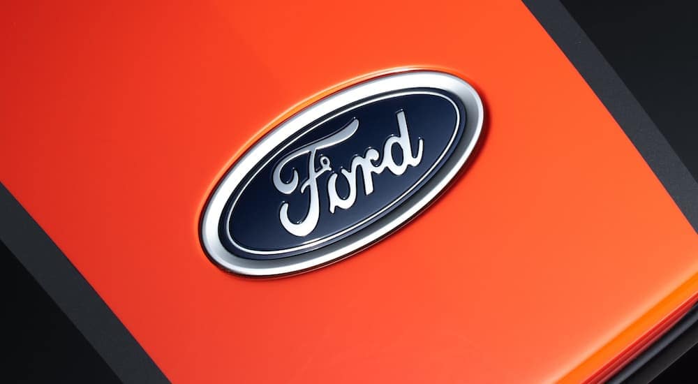 A close up shows the Ford emblem on an orange and black background.