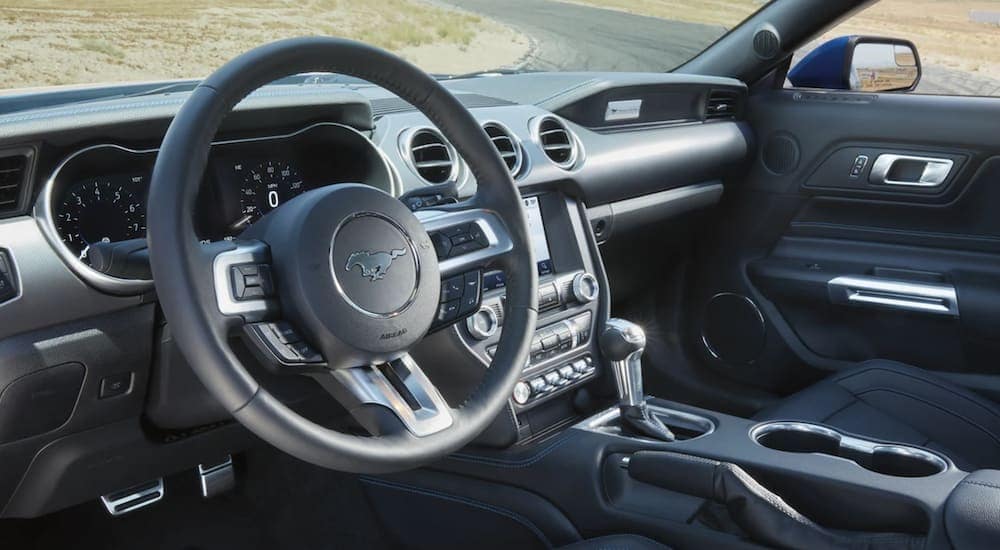 The interior of a 2021 Ford Mustang shows the steering wheel and infotainment screen.