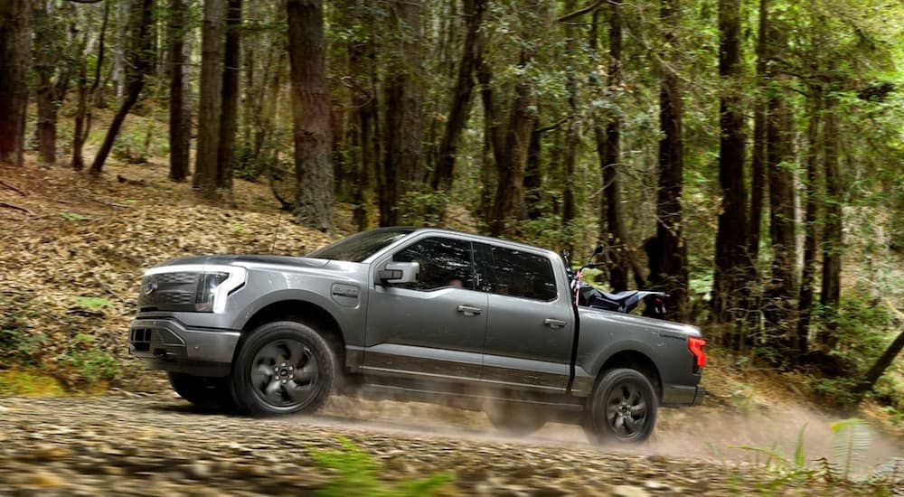 A grey 2022 Ford F-150 Lighting is shown driving through the woods after leaving a Tennessee Ford truck dealer.