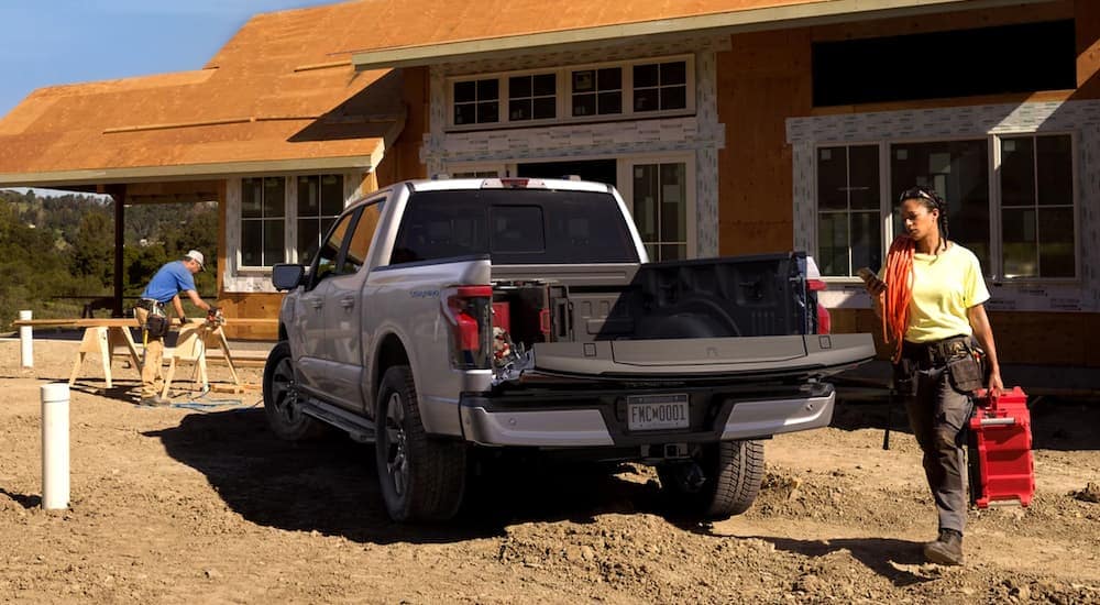 A white 2022 Ford F-150 Lightning is being used at a construction site.