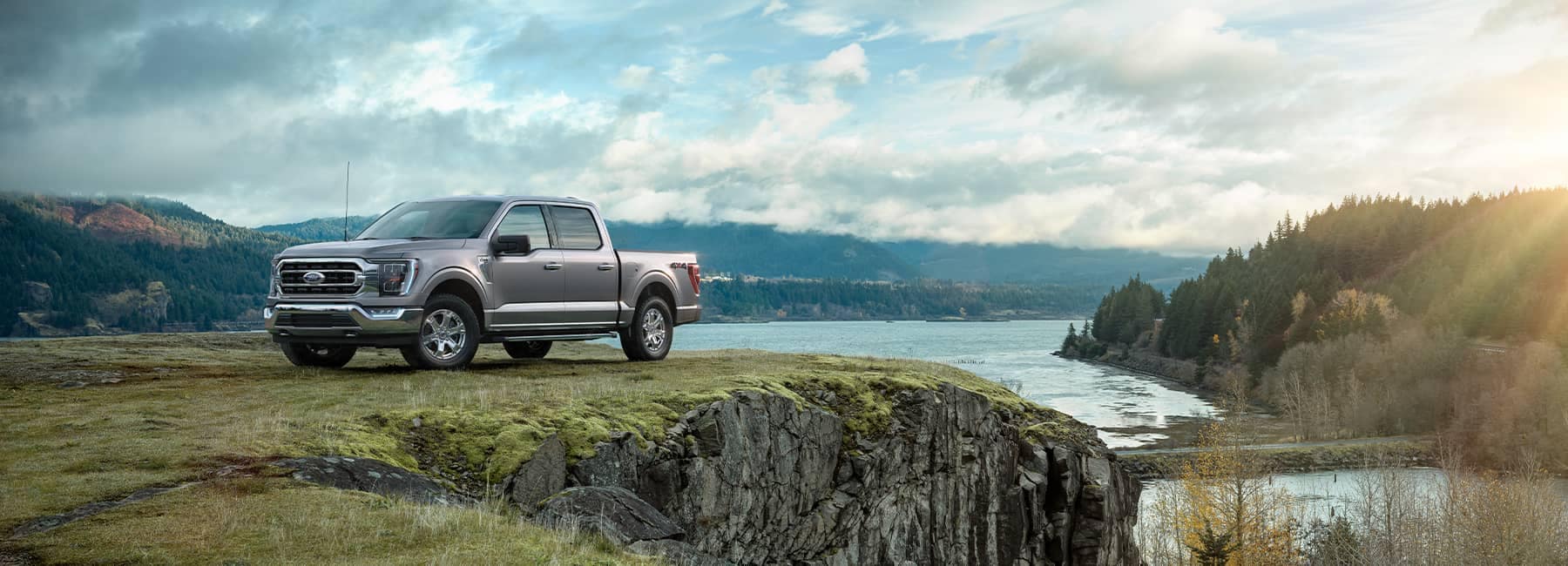 Silver 2021 Ford F-150 parked on a cliff overlooking a river