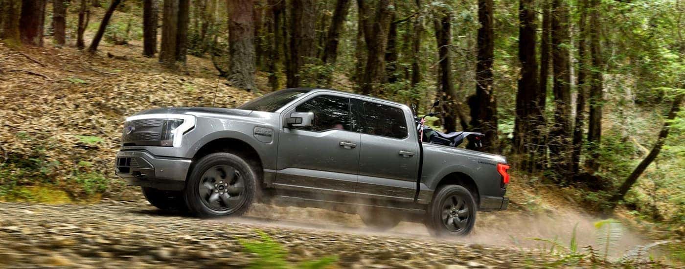 A silver 2022 Ford Lightening is shown driving through the woods after leaving a Lynchburg Ford dealership.