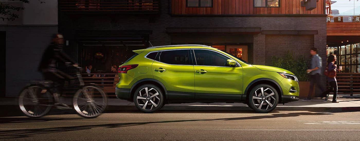 A lime green 2021 Nissan Rogue Sport is shown from the side while parked in front of a busy cafe after leaving a Nashville Nissan dealer.