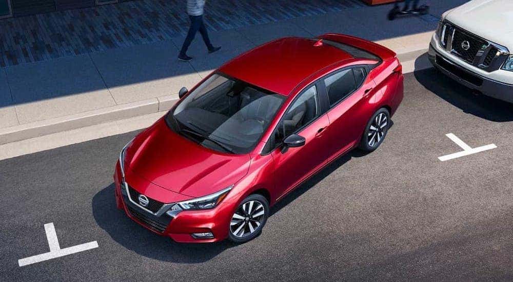 A red 2021 Nissan Versa is shown from above parallel parking on a street.
