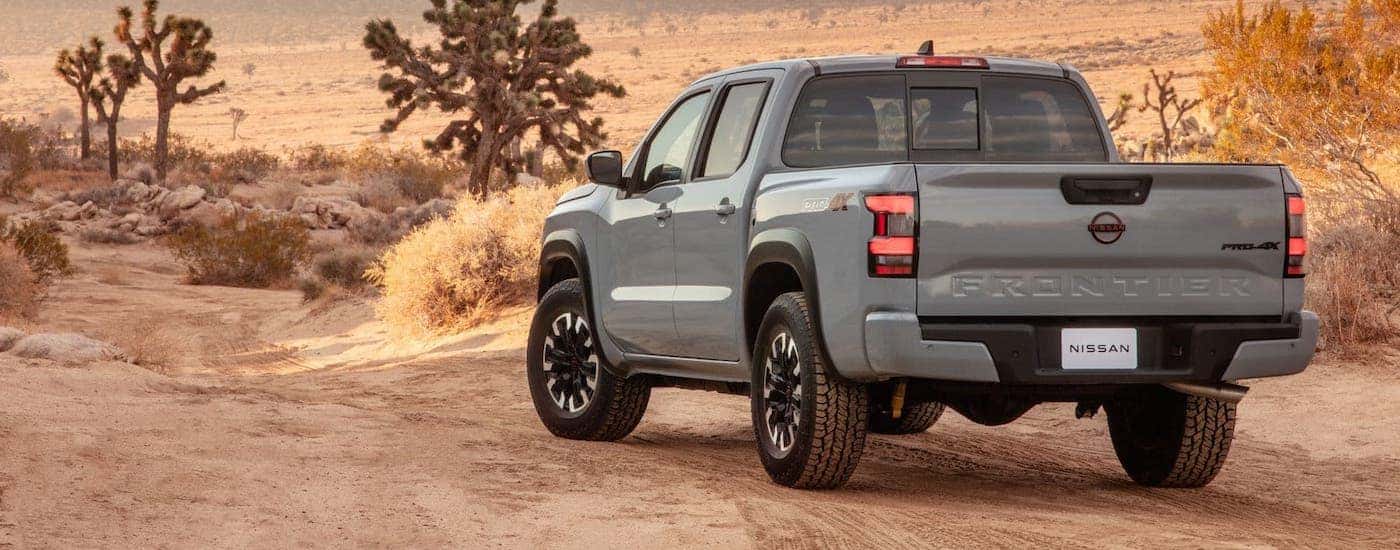 A gray 2022 Nissan Frontier is shown from the rear on a desert trail.