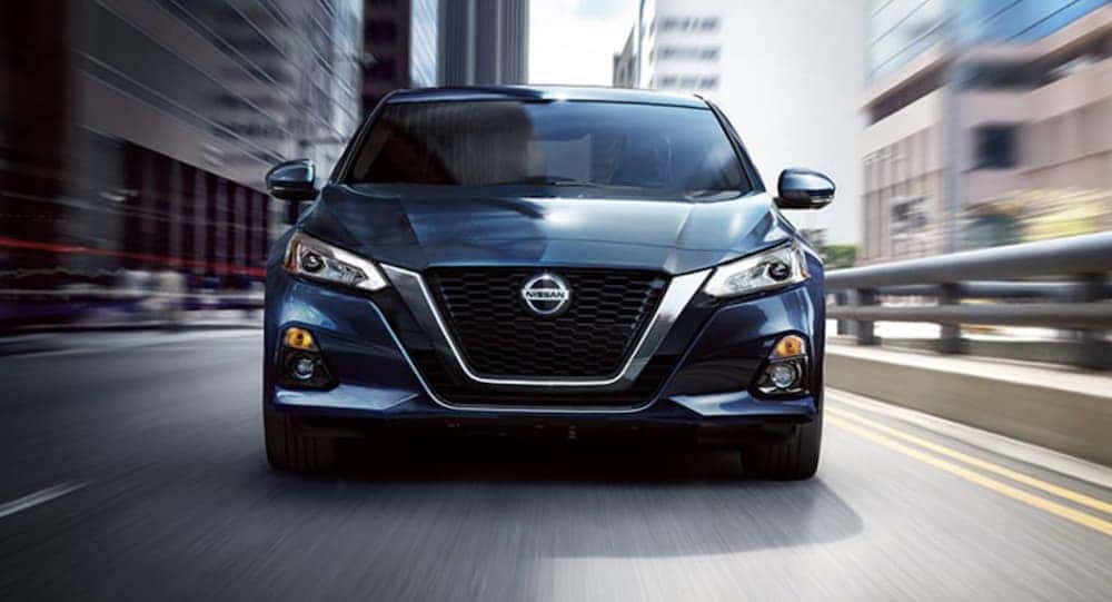 A blue 2020 Nissan Altima is shown from the front on a city street.