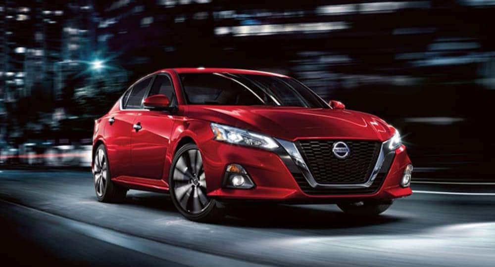 A red 2020 Nissan Altima is in a city at night.