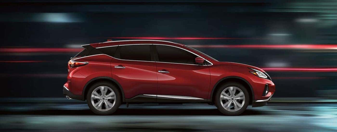 A red 2020 Nissan Murano is driving past blurred lights at night.