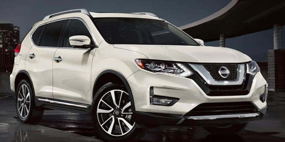 A white 2020 Nissan Rogue is sparked in a city at night.