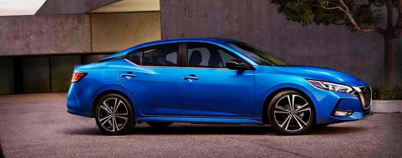 A blue 2020 Nissan Sentra is parked in front of a concrete building.
