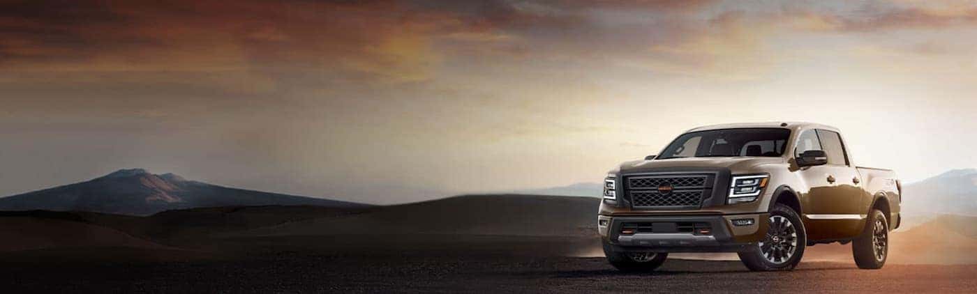 A tan 2020 Nissan Titan is parked in a desert at sunset.