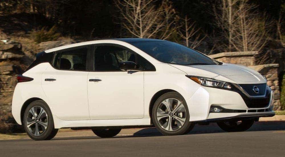 A white 2021 Nissan LEAF is driving in front of rock formations in a park.