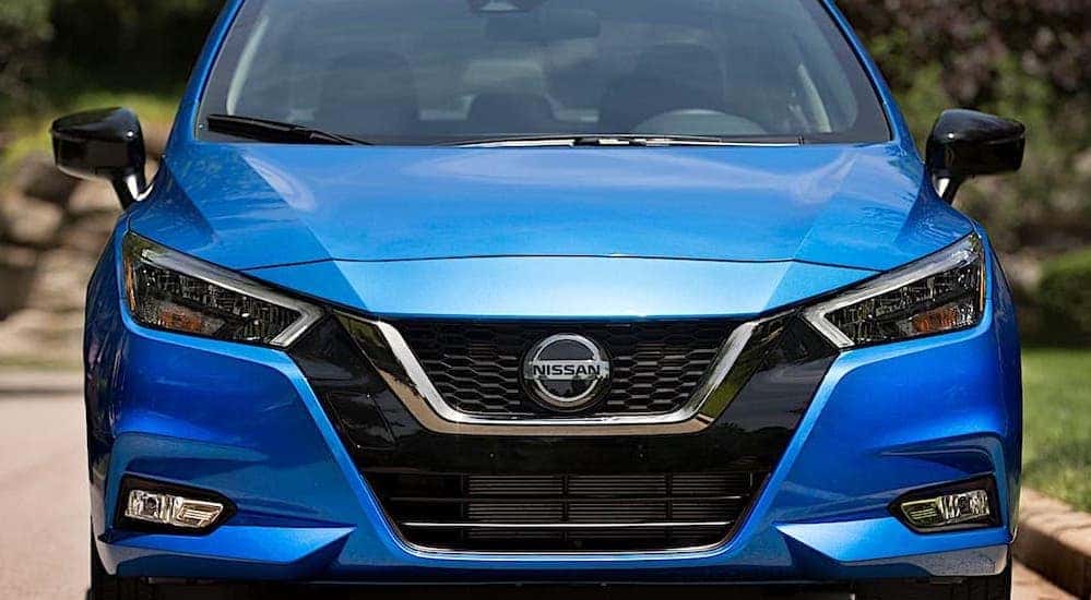 A blue 2021 Nissan Versa is shown from the front on a suburban street.