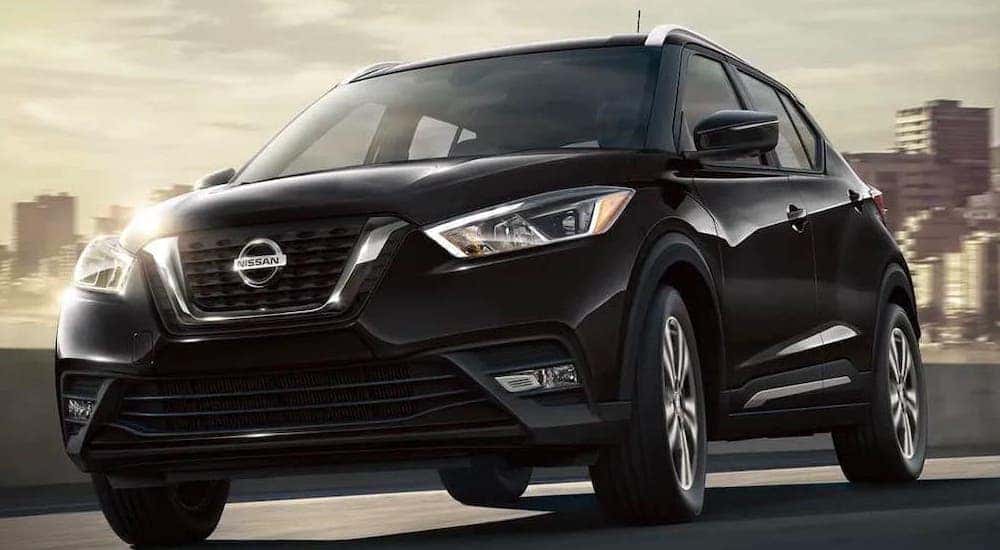 A black 2021 Nissan Kicks is shown from a low angle while driving away from a city.