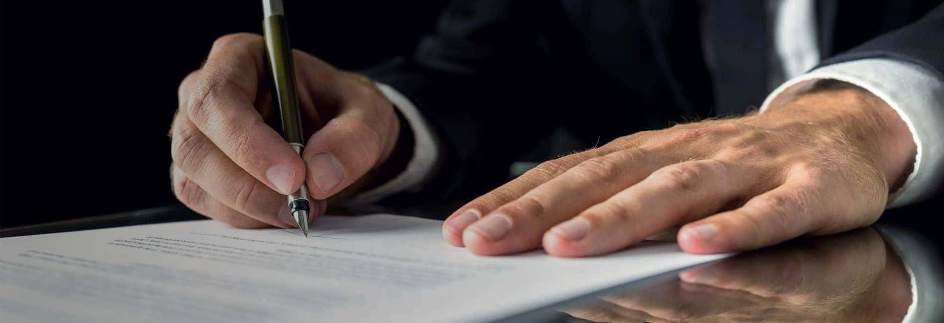 Hands of Man in Suit Signing Documents