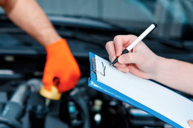 Car mechanics at the service station fills out checklist