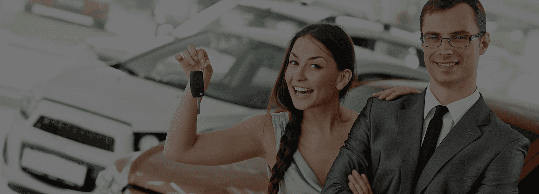 happy customer holding car keys behind salesman