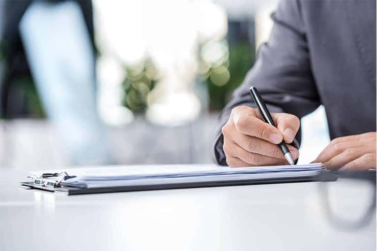 Person Signing Documents in Clipboard
