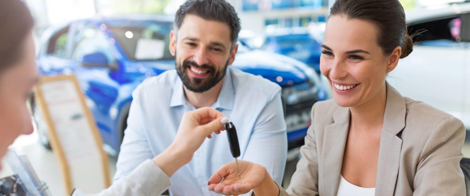 finance officer hands car key to smiling couple