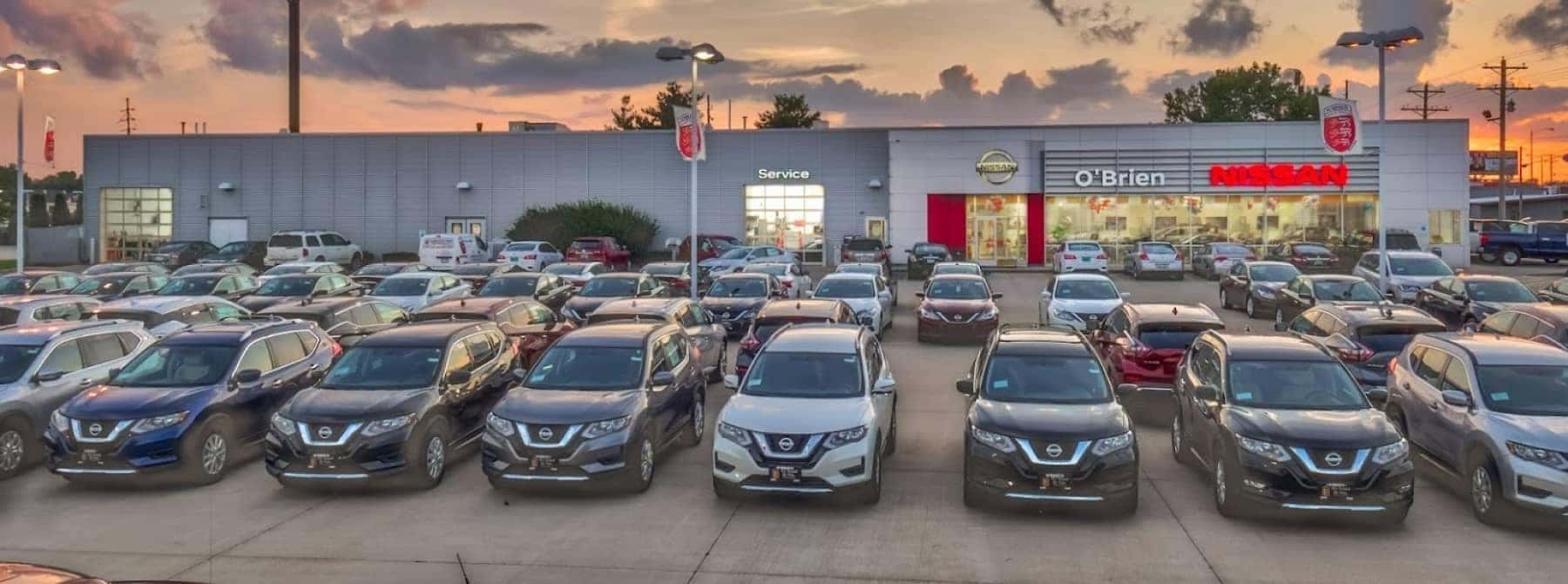 An exterior shot of a Nissan dealership at sunset