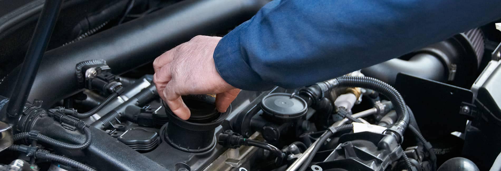 Close up image of a service technician checking the fluid levels of a car engine