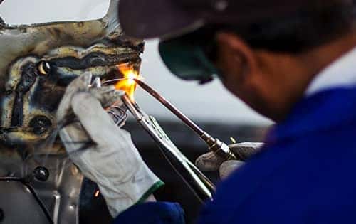 technician using a torch to fix a car