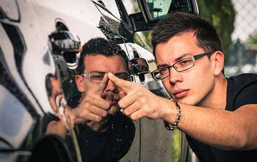 service technician running his finger along a shiny car door