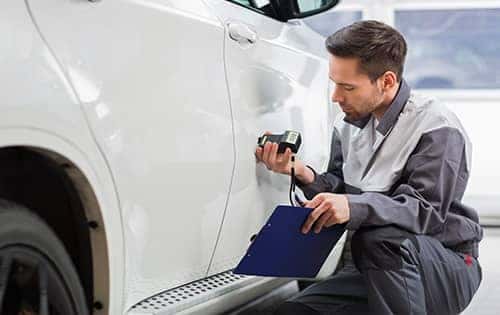 service technician looking over car paint