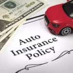 a piece of paper with a red car on it, three 20 dollar bills, and the words Auto Insurance Policy