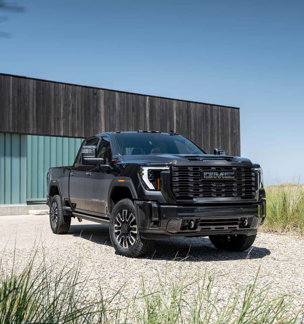 A black 2024 GMC Sierra 2500 parked on gravel.