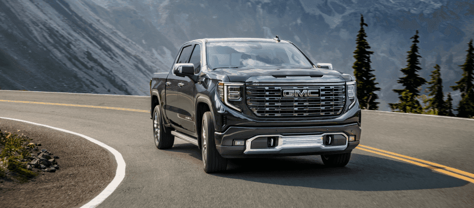 A gray 2024 GMC Sierra 1500 driving on a highway.