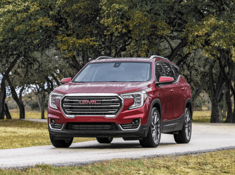 A red 2024 GMC Terrain parked near trees.