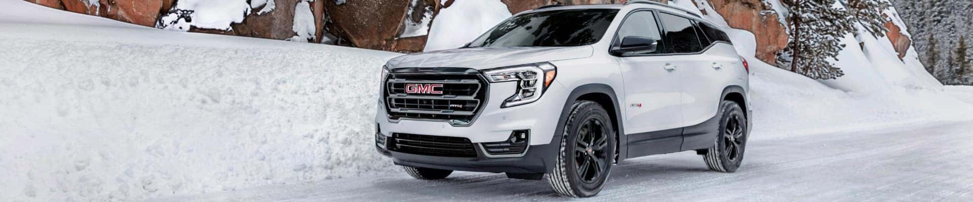 A white 2024 GMC Terrain AT4 parked on a snowy road.