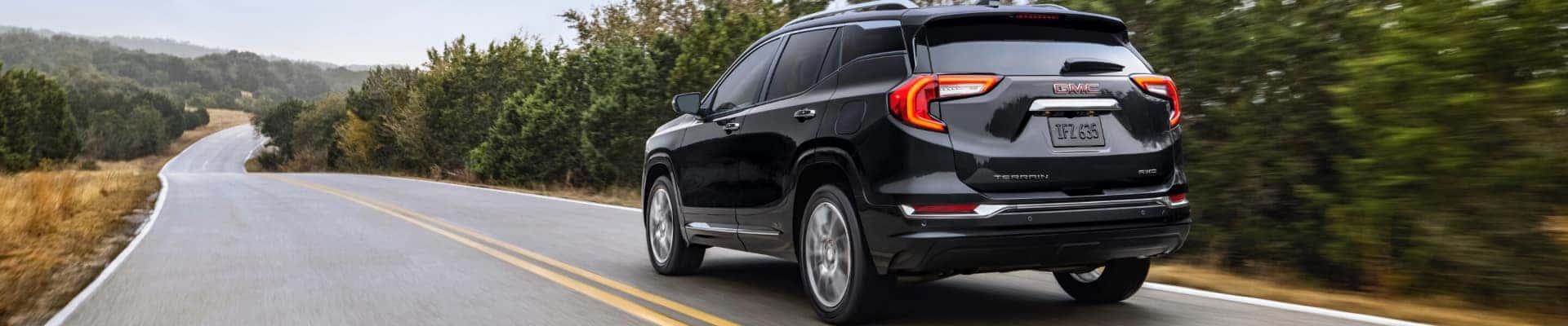 A black 2024 GMC Terrain Denali driving on a highway.