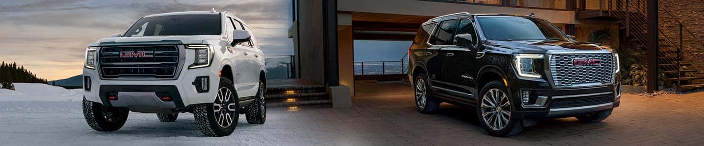 A white 2023 GMC Yukon and a Black 2022 GMC Yukon facing different directions.