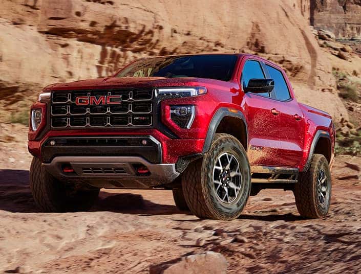 A red GMC Canyon AT4X parked off-road.