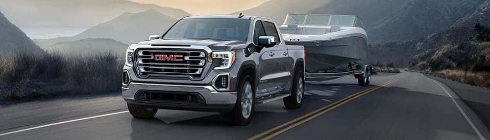 A silver 2024 GMC Sierra 1500 towing a boat.