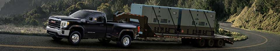 A black 2024 GMC Sierra 3500 towing a trailer.