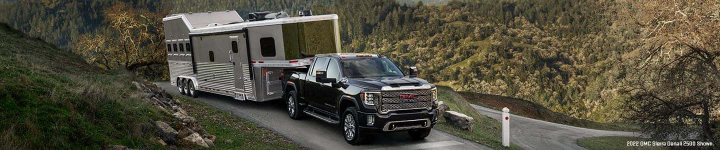 A black 2024 GMC Sierra 2500 HD towing a trailer.