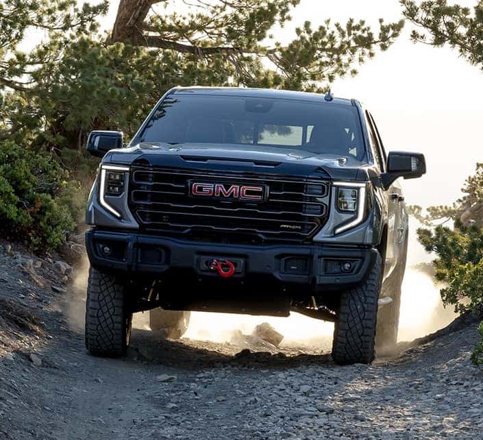 A gray 2023 GMC Sierra 1500 AT4X Specs driving off-road.